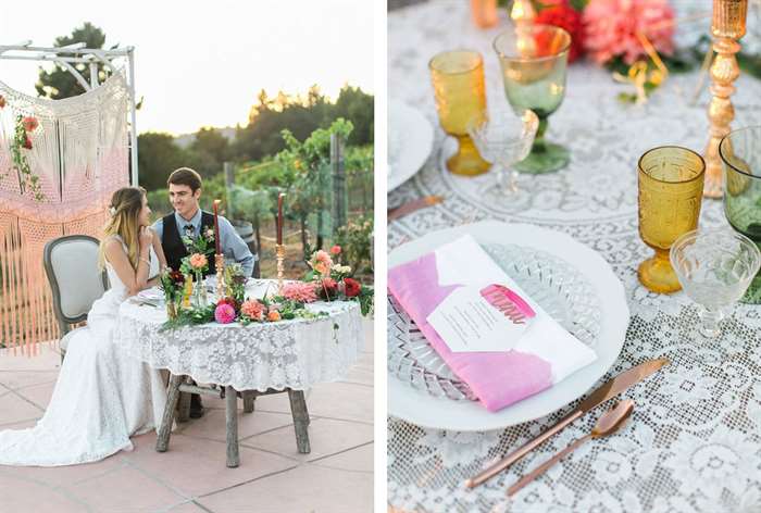 Wood table with lace tablecloth, bright flowers and tall orange candles