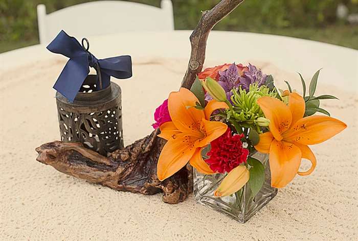 Driftwood centerpieces with bright florals and black candle votives