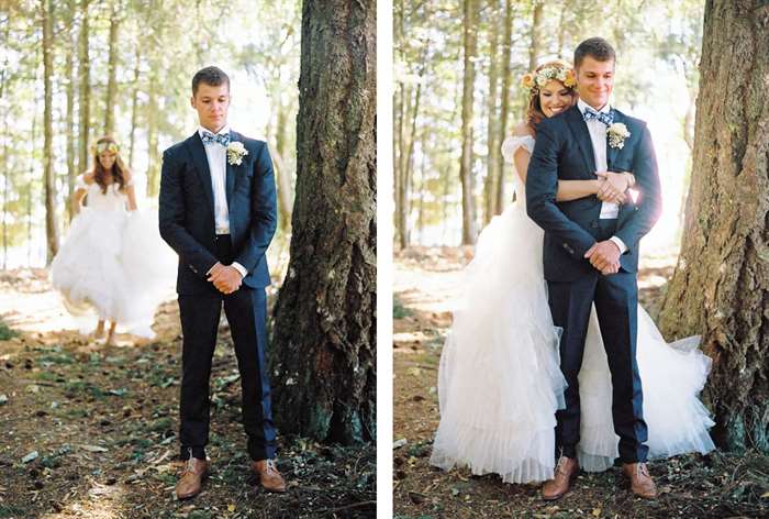 Bride with flower crown hugging groom from behind in the woods