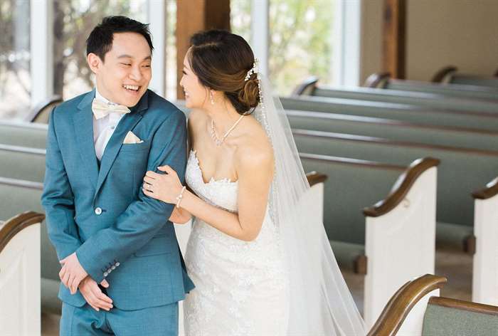 Bride hugging groom from behind in an empty church