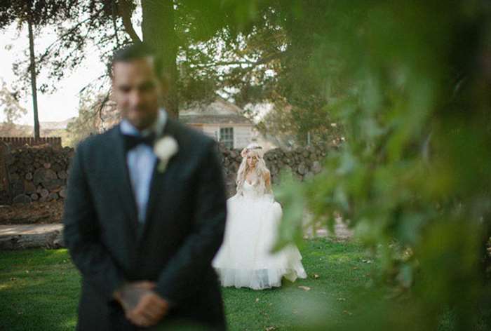 Bride in a ballgown walking up behind her awaiting groom