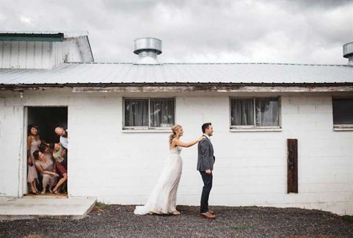 Wedding party watching as bride taps groom on the shoulder