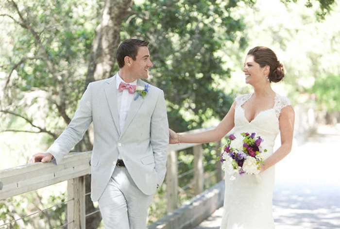 Bride holding groom's arm on a bridge 