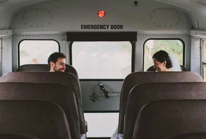 Bride and groom sitting on the back of a school bus