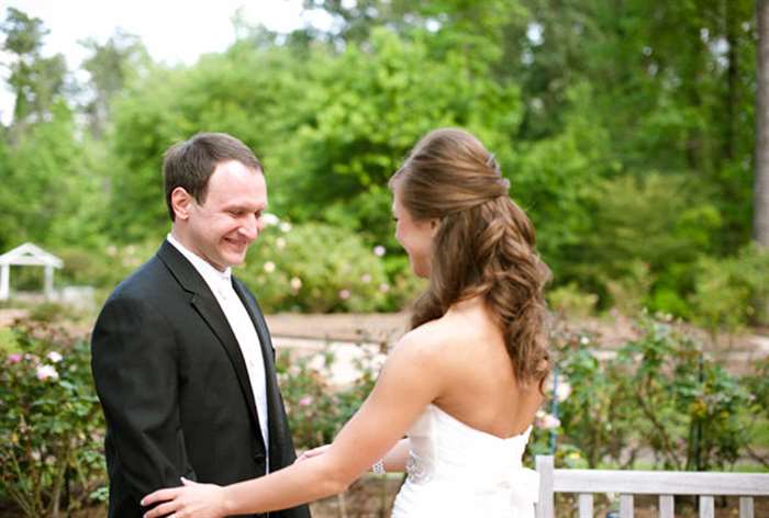 Bride holding groom's arms outside 