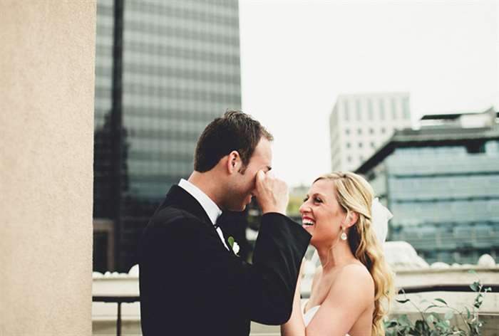 Teary eyed groom and smiling bride standing on balcony