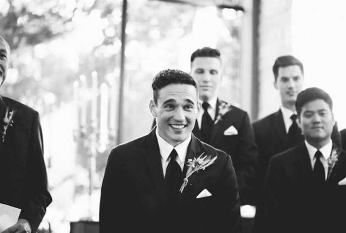 Smiling groom standing at alter with groomsmen in the back