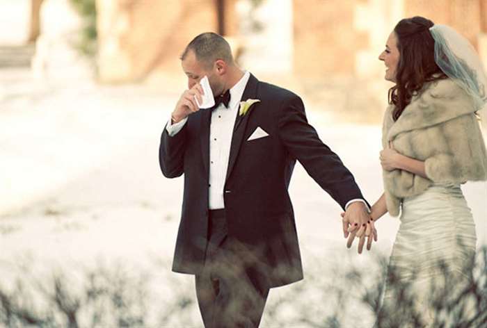 Groom wiping tears away while holding bride's hand