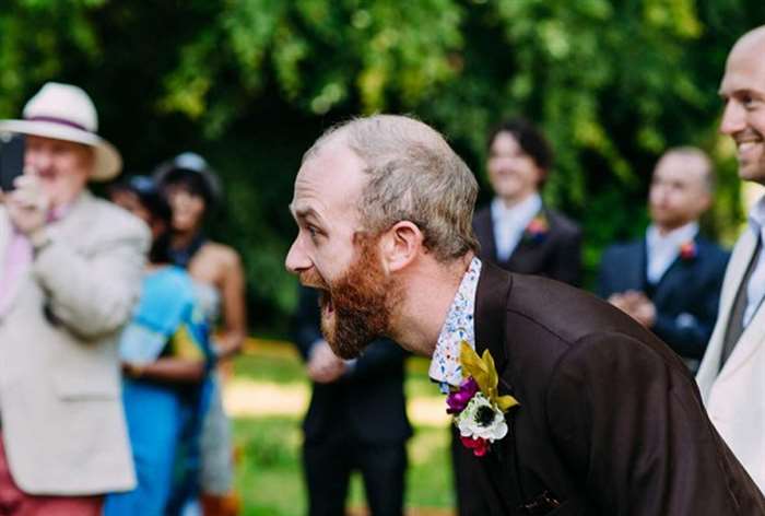 Profile shot of groom gasping while standing at the alter