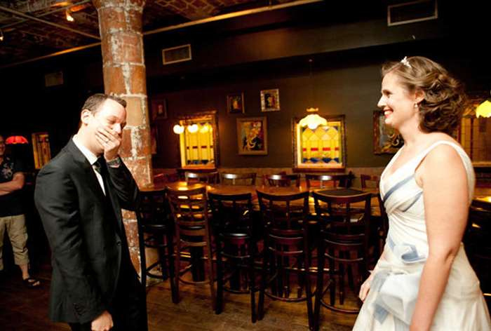 Groom covering mouth while looking at bride