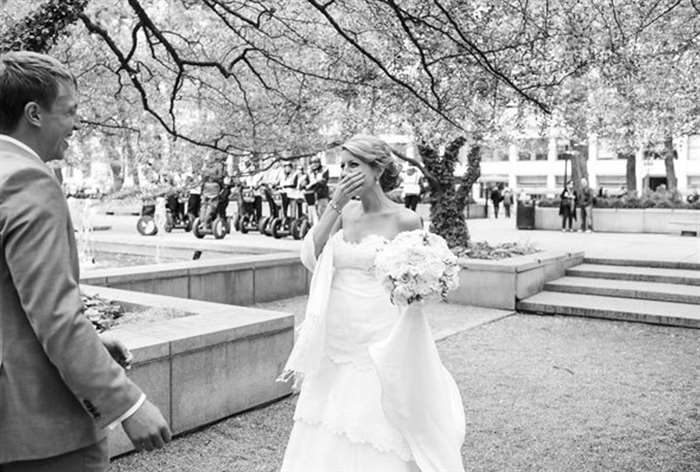 Bride holding bouquet and covering mouth while looking at groom