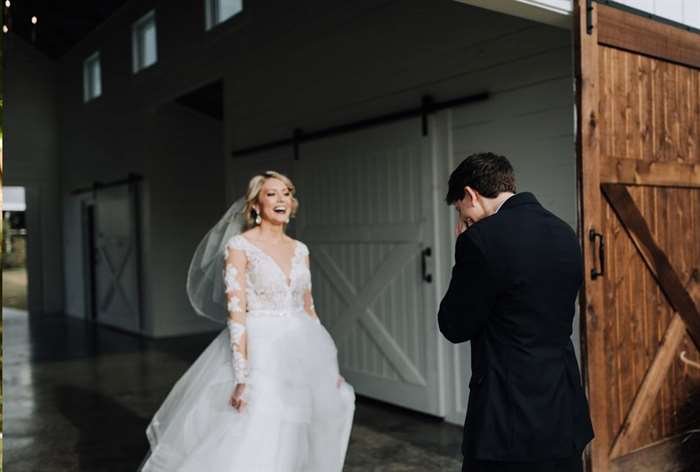 Bride smiling at emotional groom in a barn