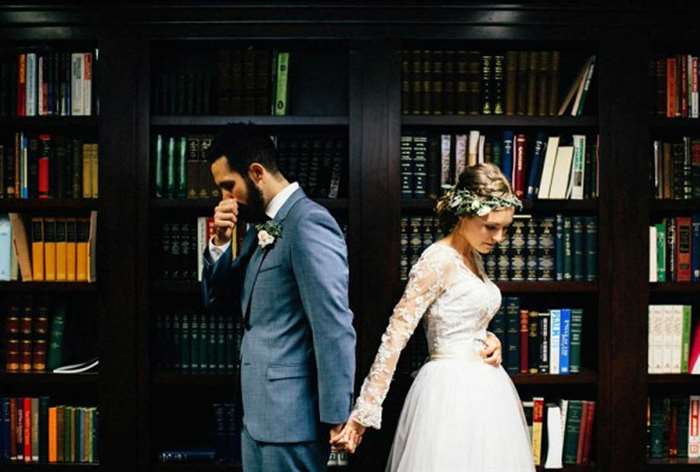 Couple holding hands back to back in a library 