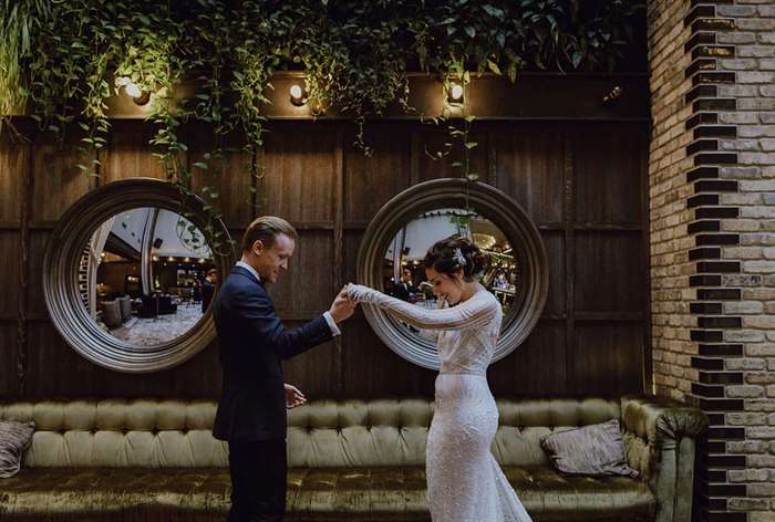 Groom admiring bride with greenery and mirrors in the background