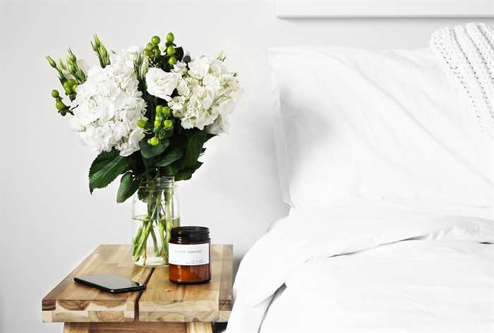 Vase of flowers next to bed. 