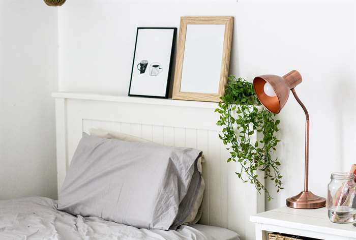 Bed with gray sheets and picture frames. 