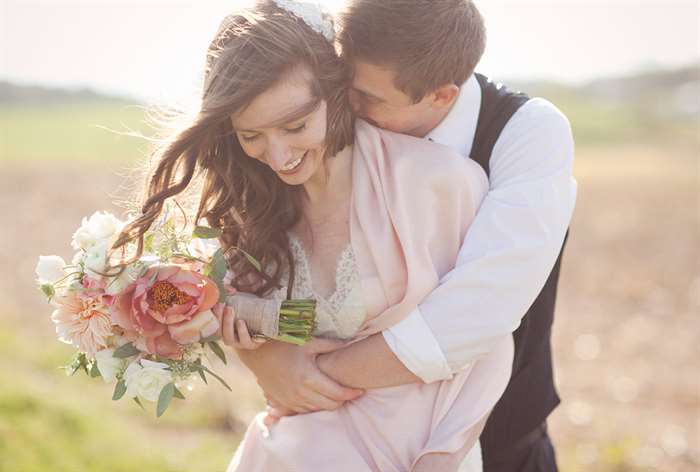 Married couple hugging in field.