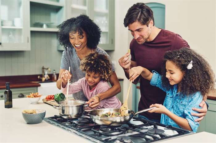 Gia đình bốn người nấu ăn cùng nhau trong nhà bếp của họ tại nhà