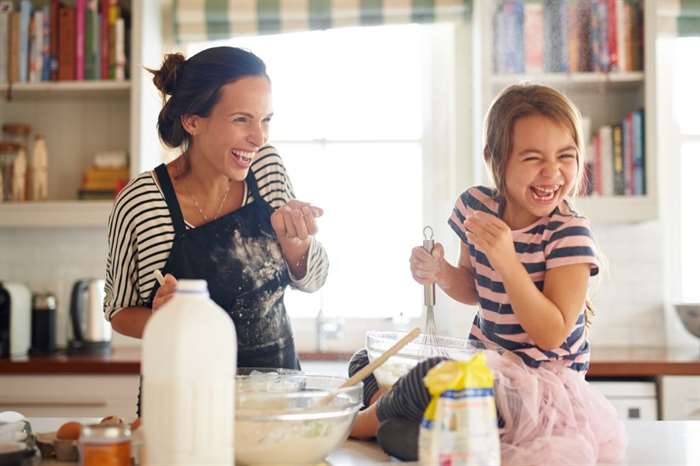 Cảnh một cô bé vui vẻ làm bánh với mẹ trong bếp