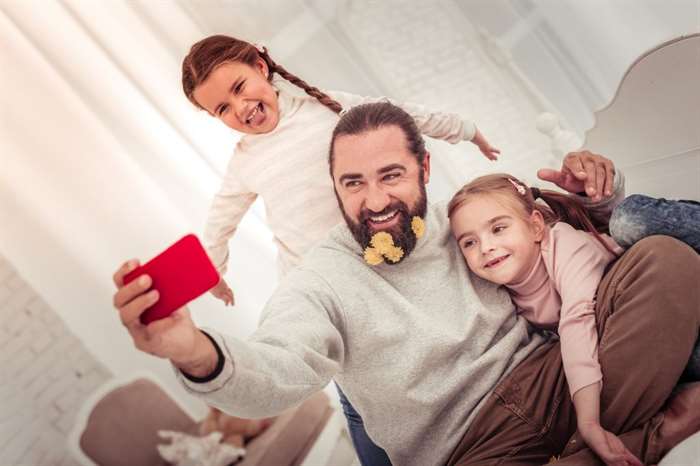 Father looks into the camera while taking a photo with his daughters together