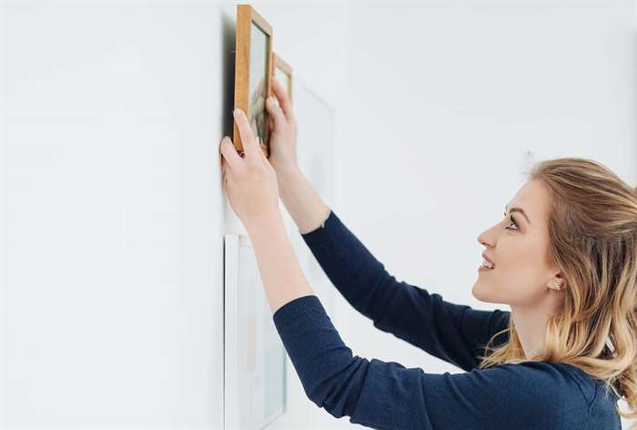 Woman hanging up a photo in her home