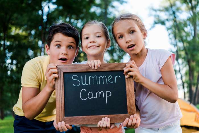 kids holding sign for at home summer camp