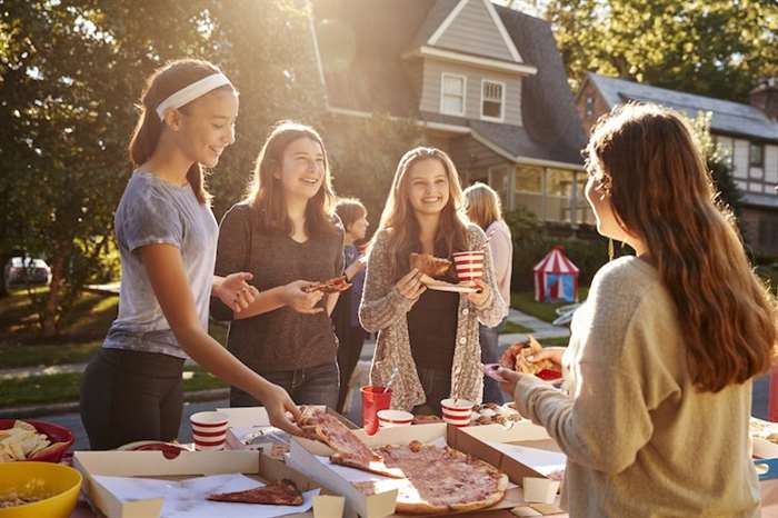 Các cô gái tuổi teen ăn pizza và nói chuyện trong một bữa tiệc khối
