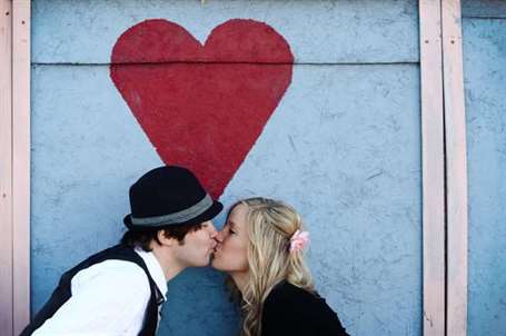 Cặp đôi hôn nhau trước bức tường trái tim