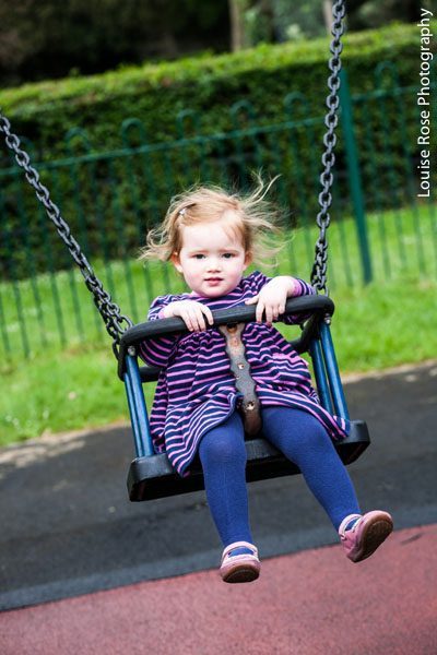 Một cô bé vui vẻ trên xích đu trong công viên từ một buổi vẽ chân dung ở Greenwich Nam London.