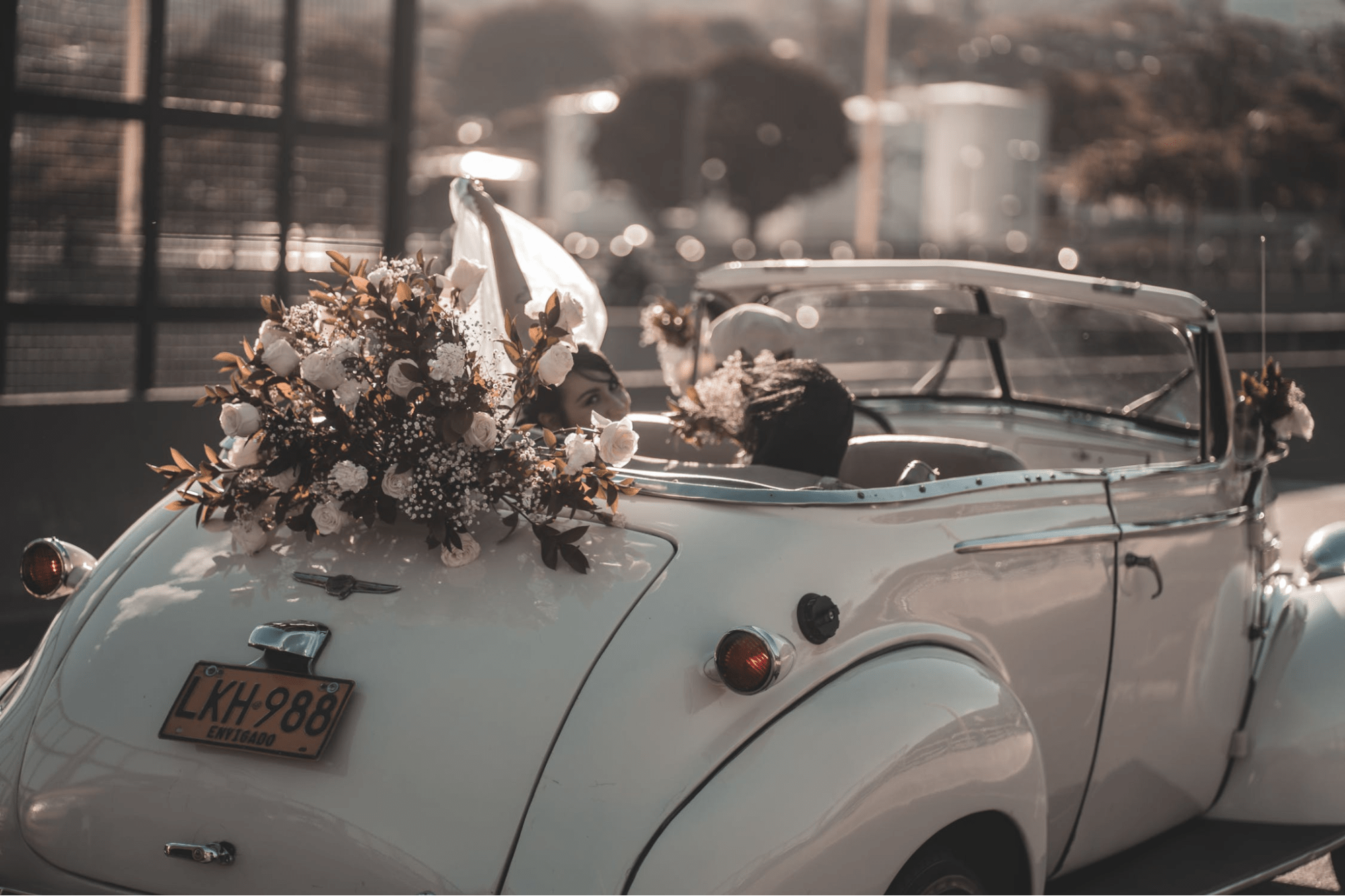Đám cưới cặp đôi lãng mạn tạo dáng trong một chiếc xe hơi